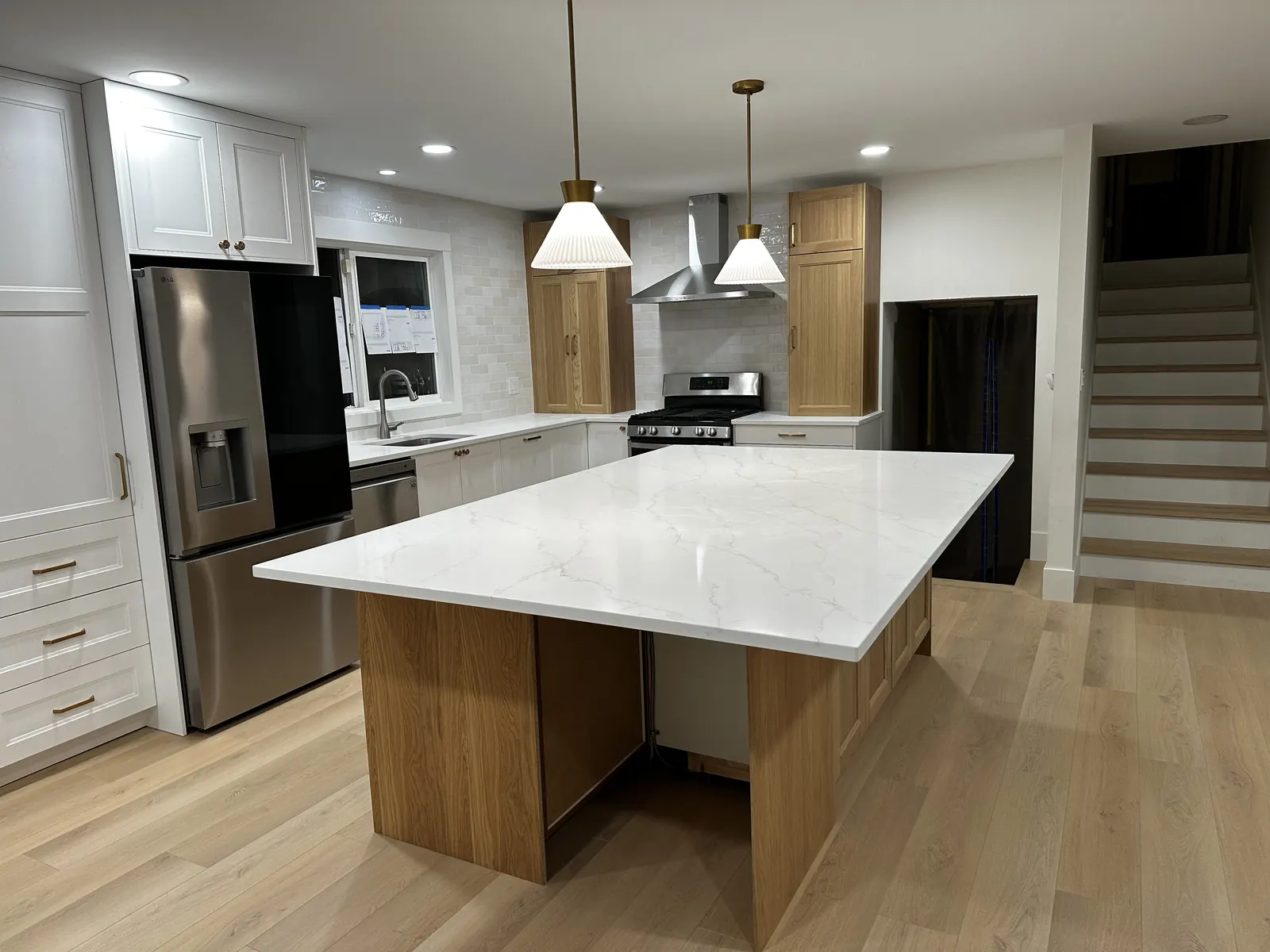 Renovated kitchen with a large white quartz island on an oak base