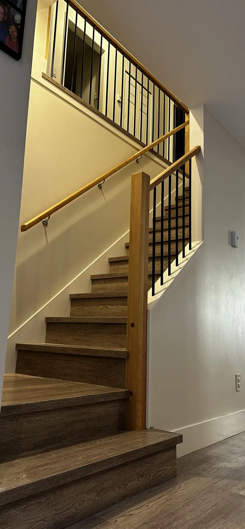 Wood staircase with an oak handrail and black metal balusters