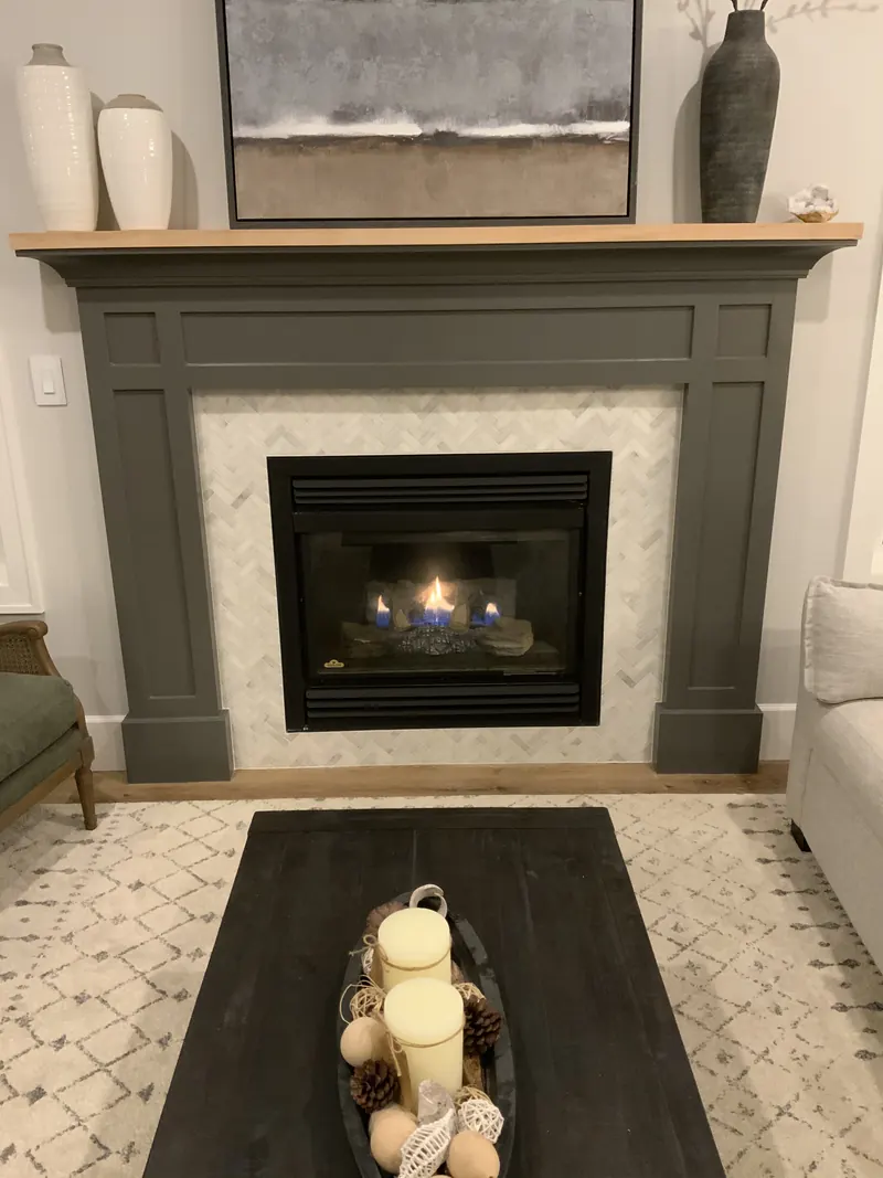 Painted wood fireplace mantel with a herringbone tile surround