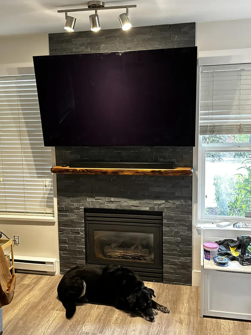 Stacked stone fireplace with a live edge mantel and wall-mounted television