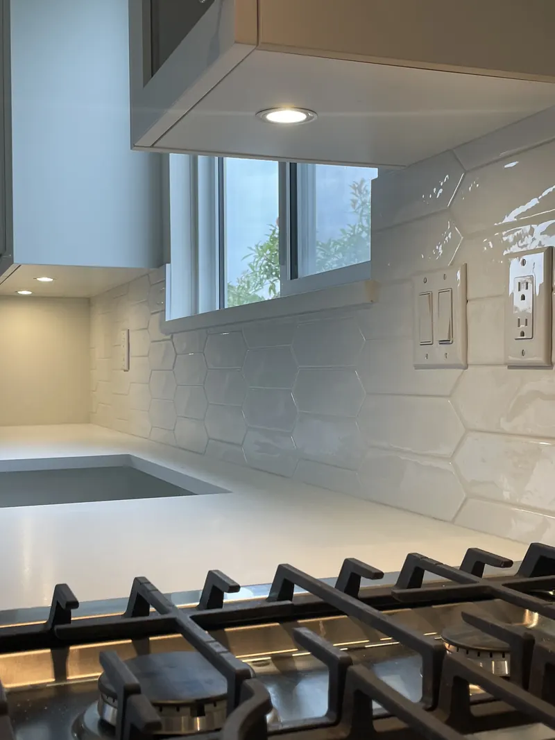 White textured tile backsplash behind a gas cooktop